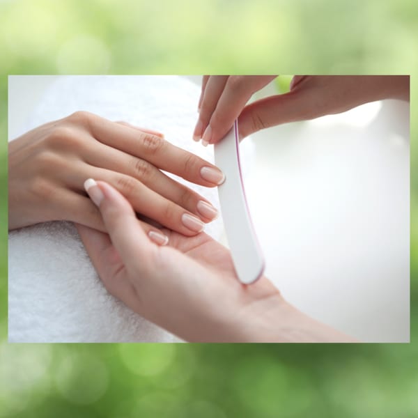 A person's hands getting a manicure, with a nail file shaping the nails.